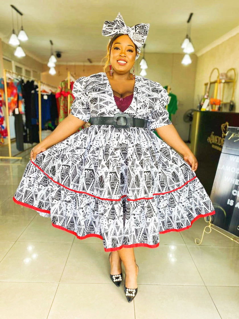 Geometric midi dress with puff sleeves, black-and-white pattern, red trim, bow belt