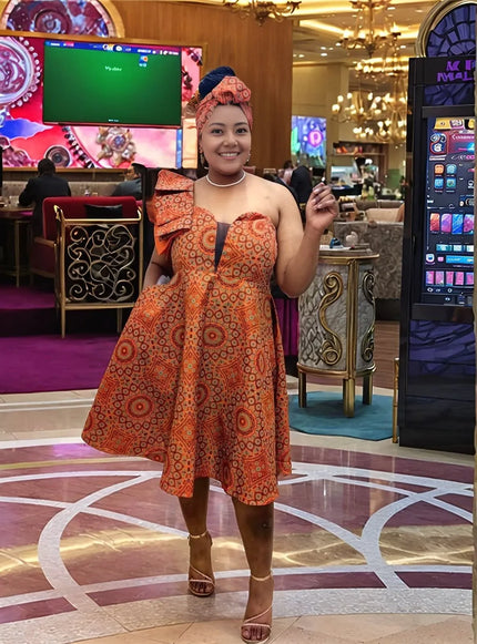 One-shoulder ruffle dress in orange-red with circular African print, flared skirt