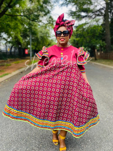 Traditional dress with ruffle sleeves, pink circle motif, rainbow trim hem.