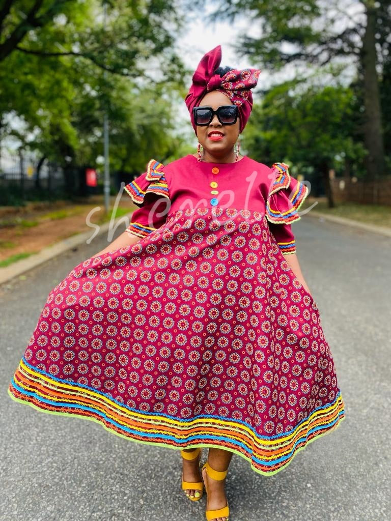 Traditional dress with ruffle sleeves, pink circle motif, rainbow trim hem.