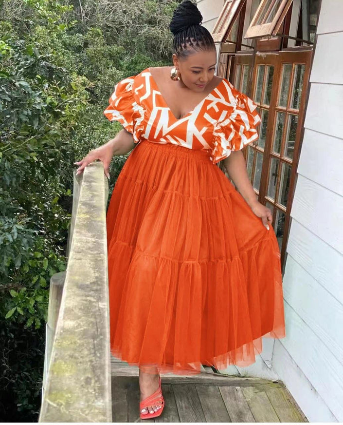 Orange-red tiered tulle maxi dress with ruffled puff sleeves and white pattern bodice