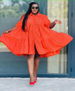 Orange-red ruffle-hem shirt dress with long sleeves and button-front, gathered flounce hem.