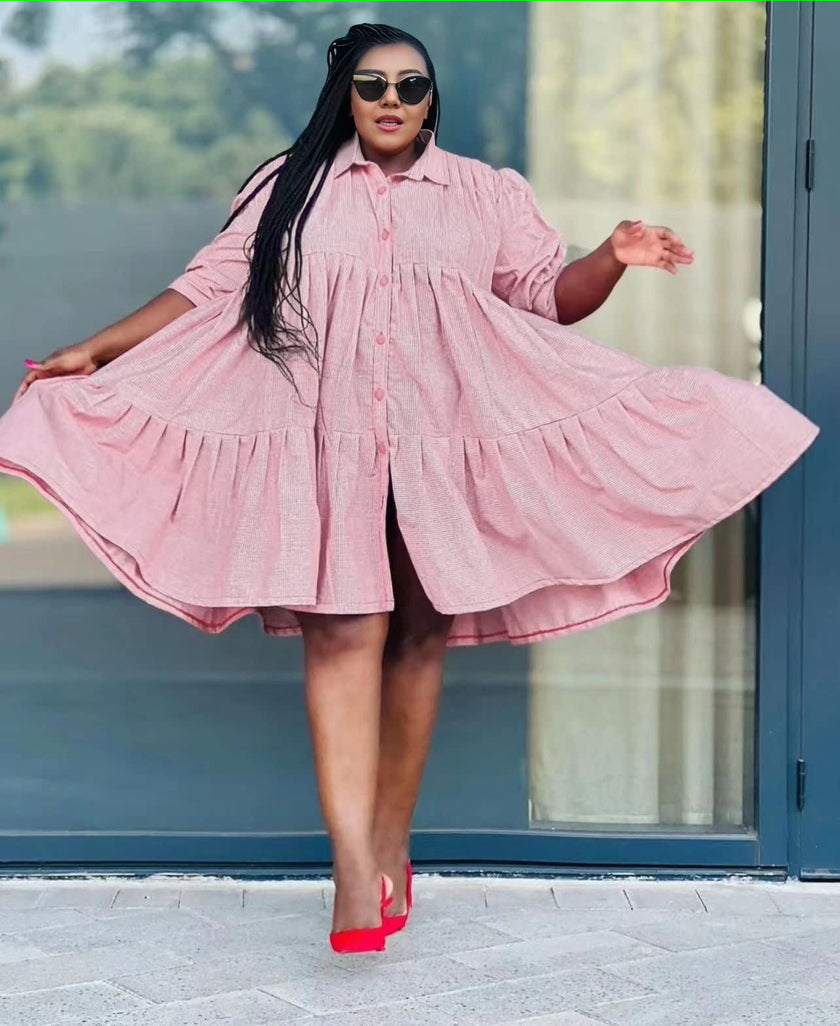 Light pink ruffle-hem shirt dress with long sleeves and button-front, pleated yoke.