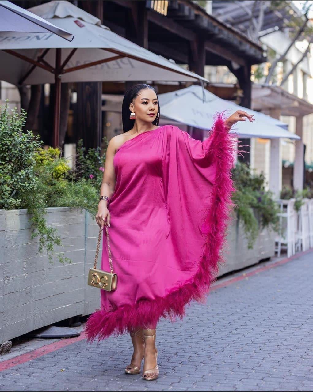One-shoulder evening dress in magenta satin, with feather trim at hem.