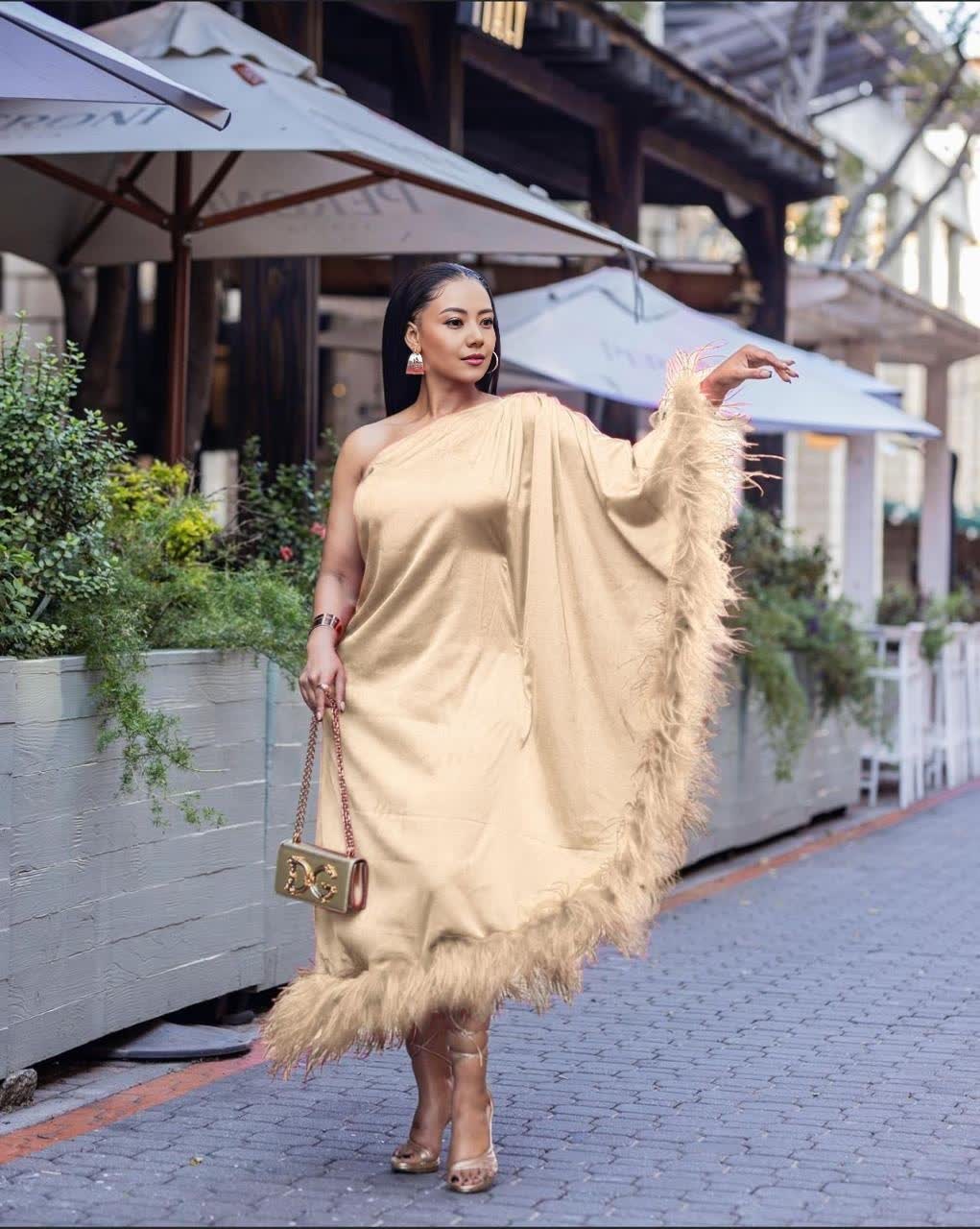 One-shoulder evening dress in beige satin, with feather trim at hem.
