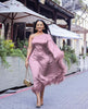 One-shoulder evening dress in mauve satin, with feather trim at hem.