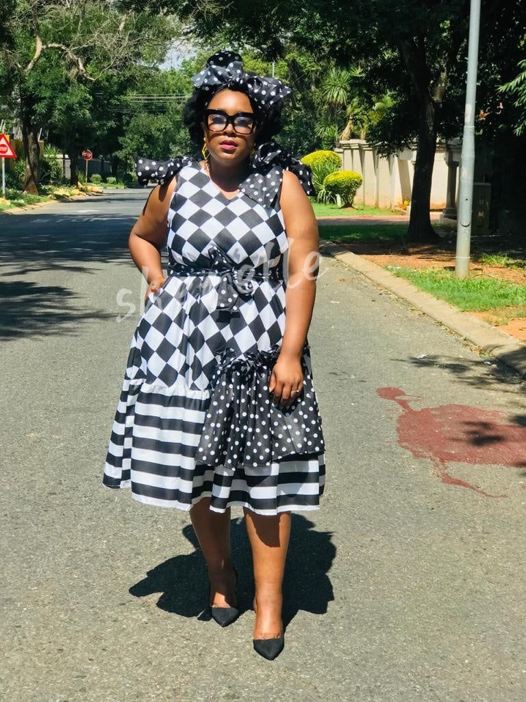 Checkered midi dress with bow waist, sleeveless black-and-white plaid skirt and polka dot overlay.