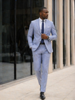 Light blue slim-fit suit with navy tie, vest, and pocket square in breast pocket