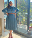 Dark blue denim midi dress with pleated high-waist skirt, button front, long sleeves.