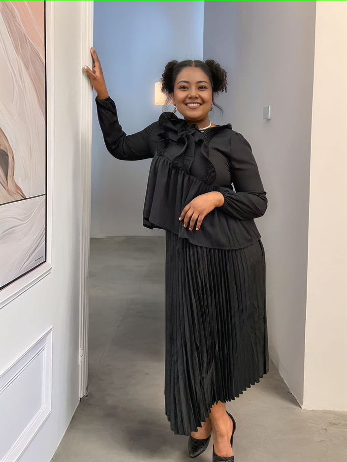 Black cinched waist pleated blouse with ruffled neckline and gathered long sleeves