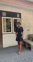 Black polka dot mini dress with a smocked waist and short puff sleeves, shown on a model.