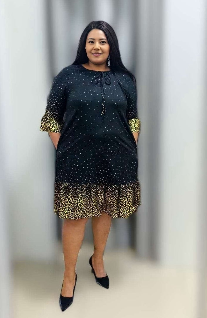Plus size polka dot ruffle dress with tie neck, black fabric and gold-trim hem and cuffs.