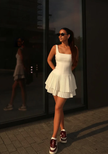 White sleeveless mini dress with pleated skirt, scoop neckline