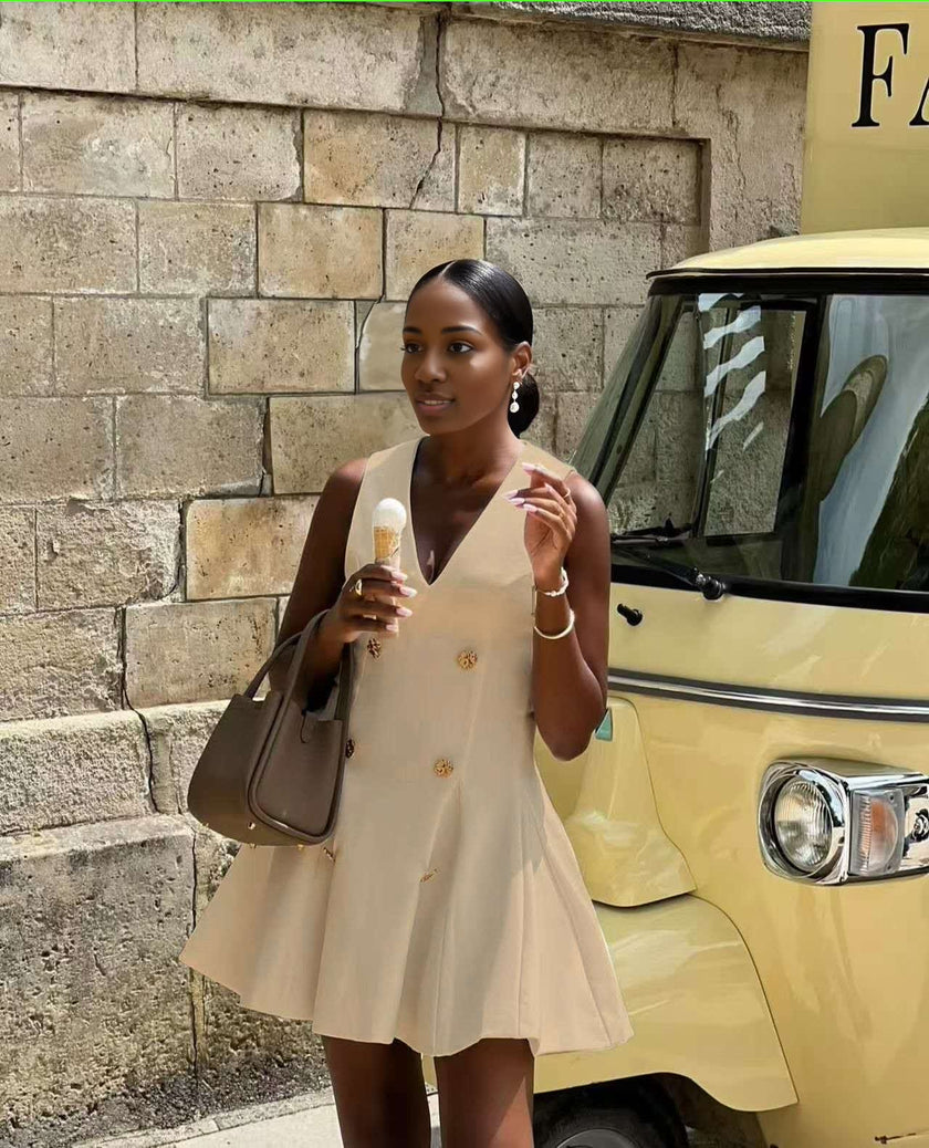 White sleeveless blazer mini dress with V-neck, gold buttons down front, pleated flared skirt.
