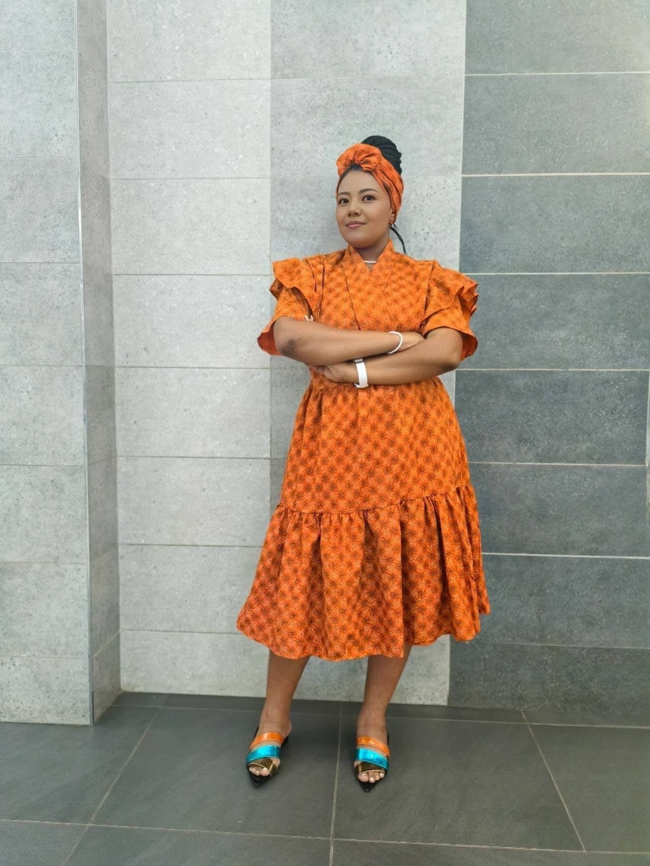 Orange midi dress with short ruffled sleeves and tiered skirt, small allover pattern