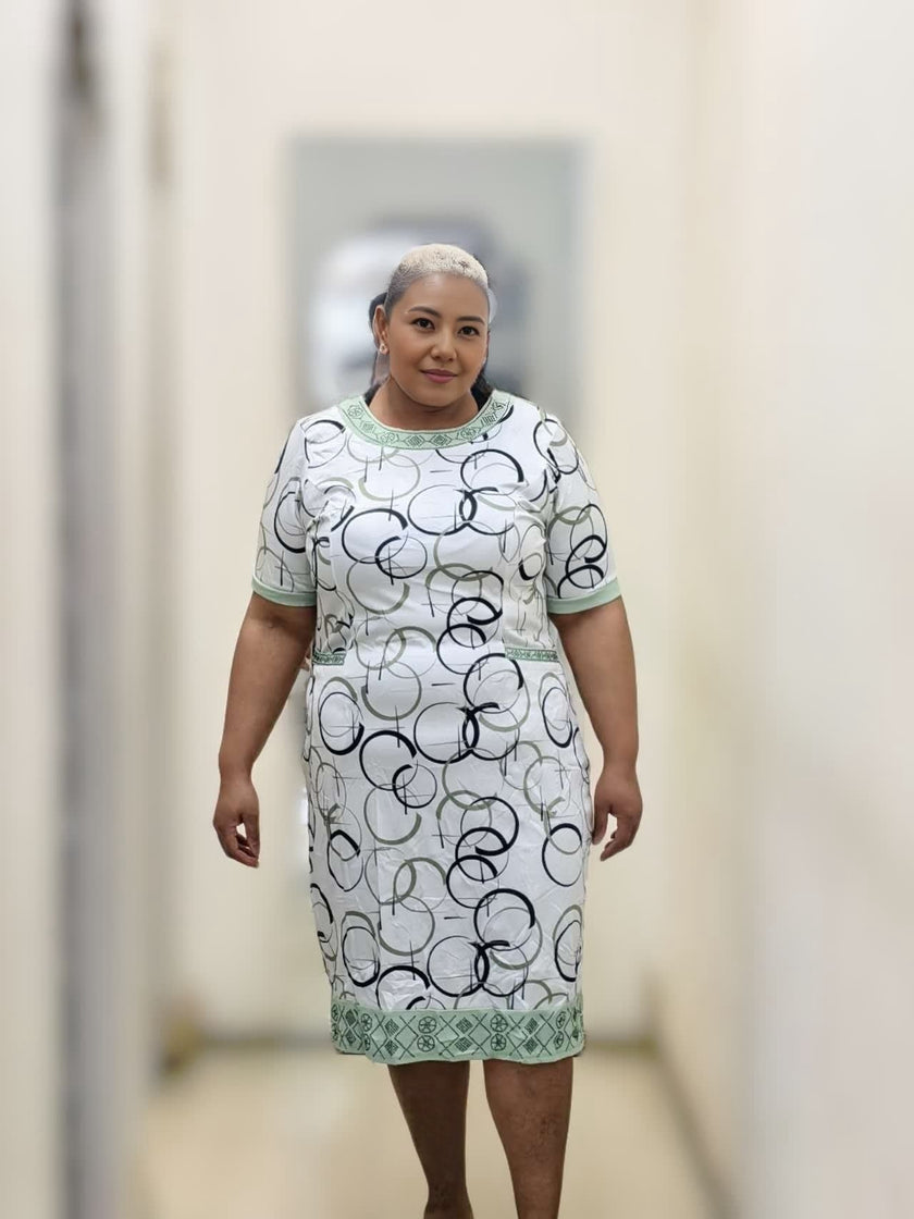 Midi dress in white with geometric circle print, light green crew neckline and hem trim.
