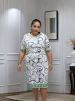 Midi dress with white geometric circle print, light green trim at neck and hem, short sleeves.