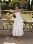 White midi dress with thin straps, fitted bodice and pleated skirt