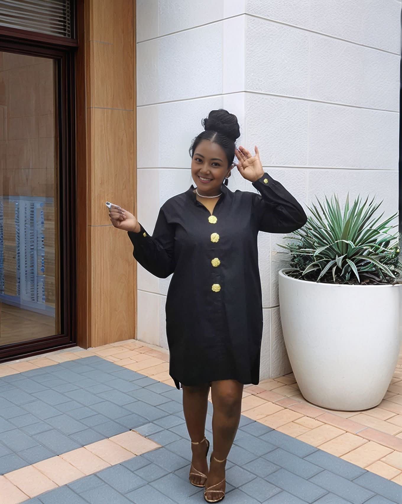 Black midi dress with five gold buttons down the front and long sleeves