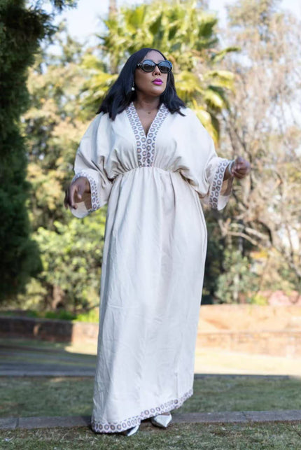 Geometric maxi dress in white with long sleeves, embroidered panel, and tiered skirt