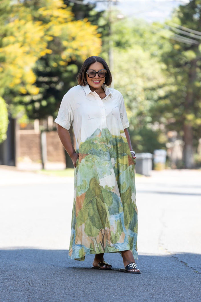 Maxi dress with white short sleeves and abstract landscape print in green, blue, and orange.