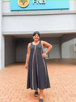 Black sleeveless A-line maxi dress with thin gold trim around the neckline and seams