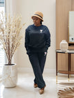 Dark two-piece jogger set with crew sweatshirt and tapered pants, small chest emblem