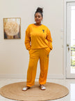 Orange two-piece jogger set with crew sweatshirt and tapered pants, small chest emblem