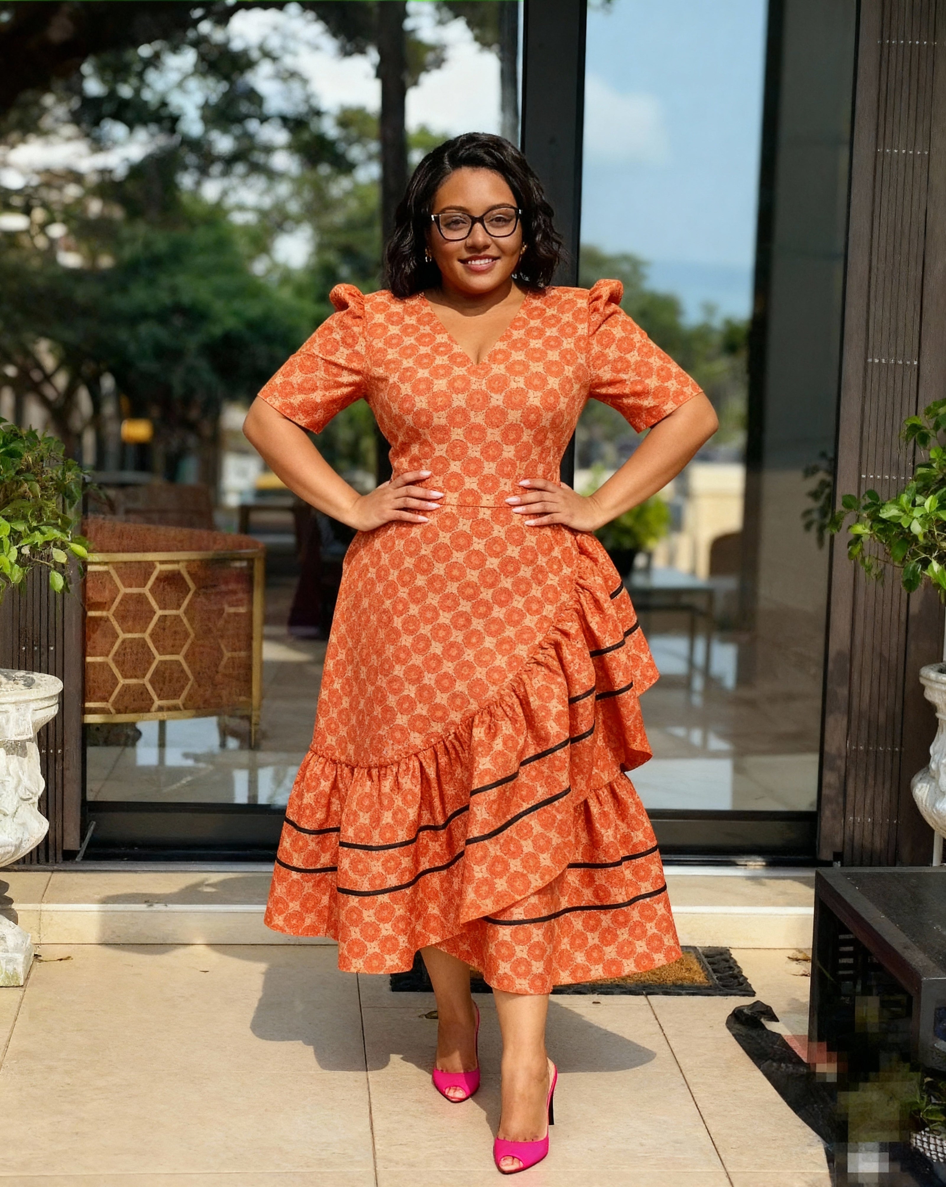 Orange patterned high-low ruffle dress with puff sleeves, V-neck, and black tiered trim