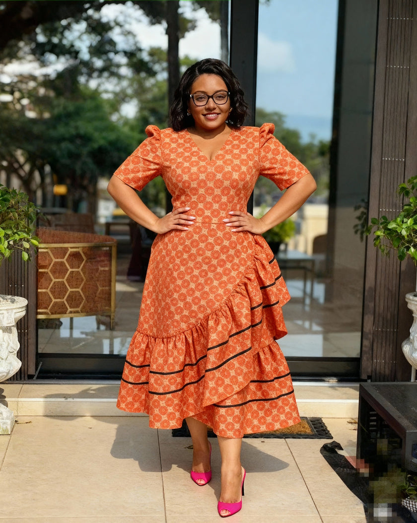 Orange patterned high-low ruffle dress with puff sleeves, V-neck, and black tiered trim