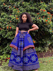 Blue African print maxi skirt with floral medallion print, orange trim, tied waistband.