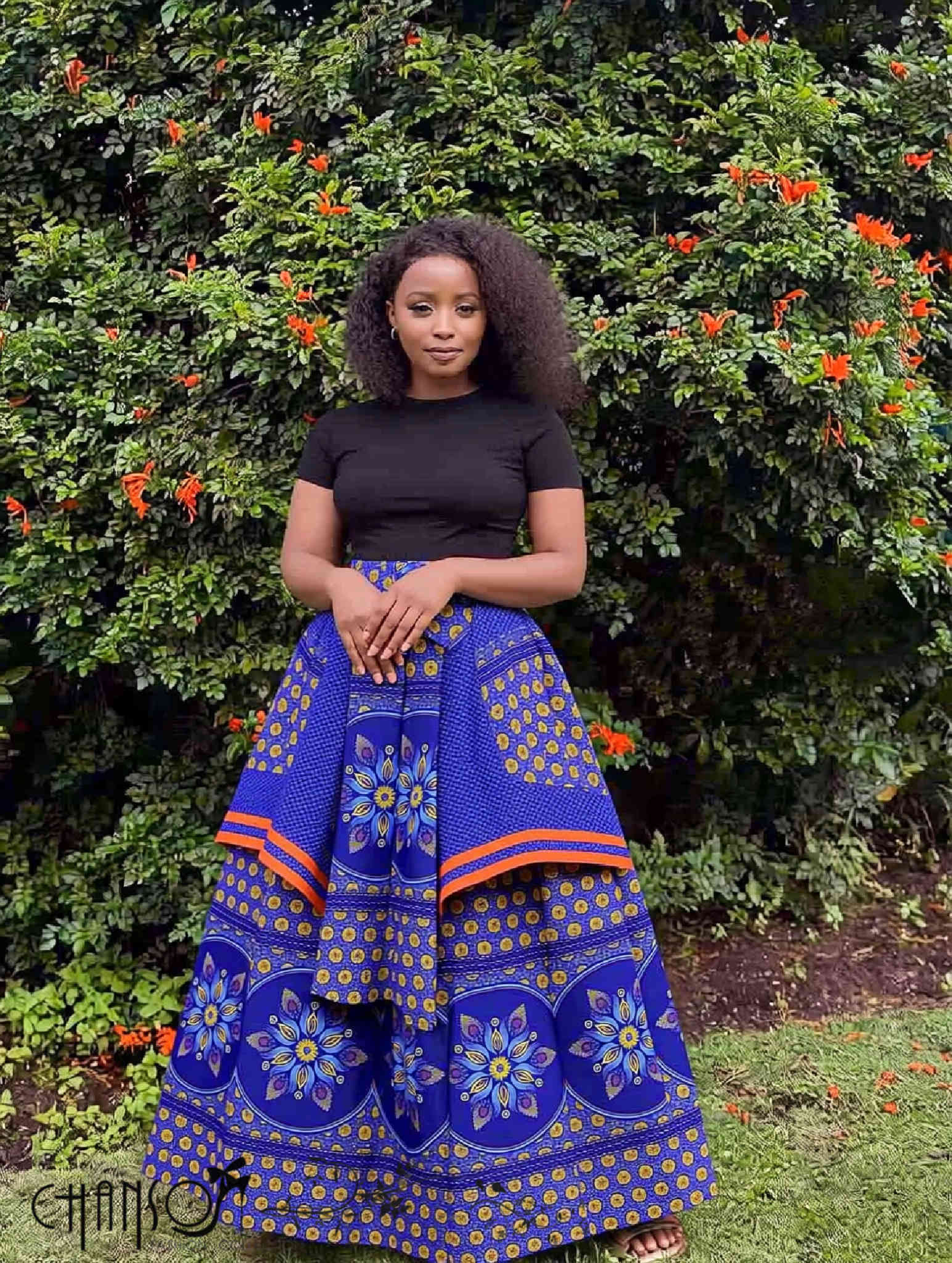 Blue African print maxi skirt with floral motifs and orange trim, full gathered flare.