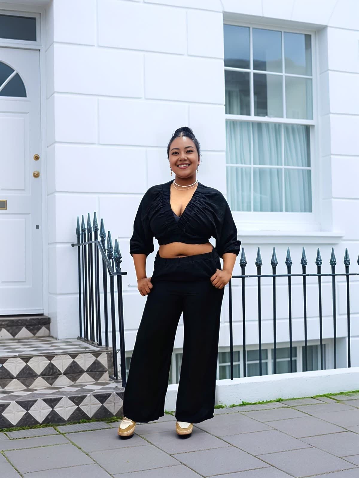 Black V-neck cropped top with ruched bust and wide-leg pants, standing full-body