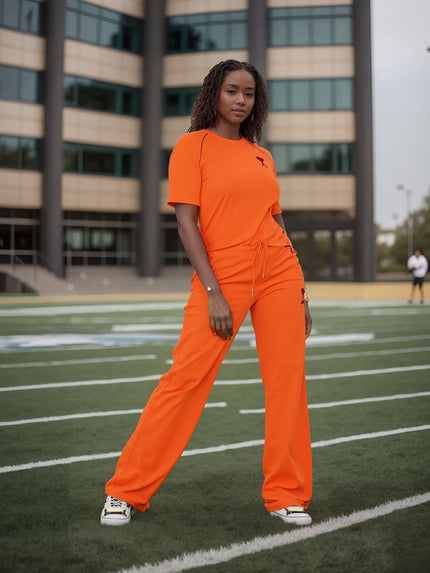 Orange-red wide-leg stretch waist pants with small red logo on leg.