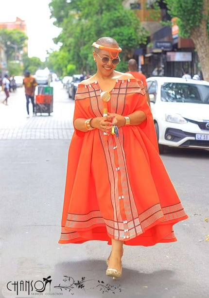 Orange-red maxi cape dress with vertical striped panel and hem border, button detail