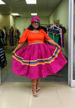 A-line midi dress with orange puff sleeves and purple patterned skirt with rainbow hem trim