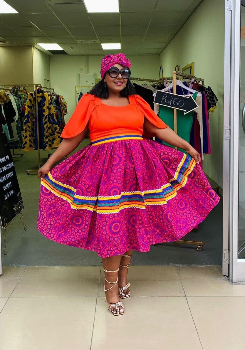 A-line midi dress with orange puff sleeves and purple patterned skirt with rainbow hem trim