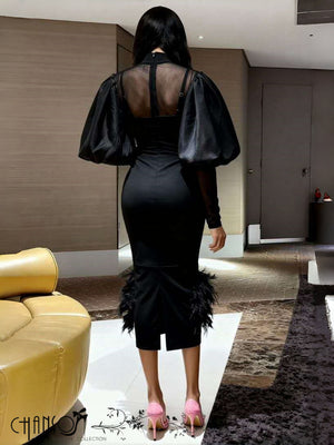 Back view: black midi dress with puff sleeves and feather hem detail