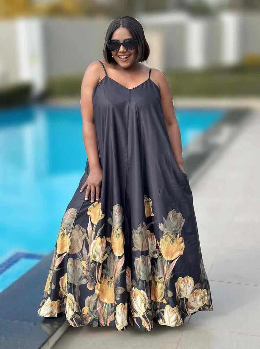 Black sleeveless maxi dress with tulip-like floral hem, thin straps, flowy skirt.
