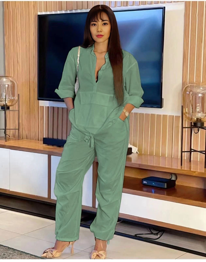 Green solid color jumpsuit with long sleeves, V-neck, and drawstring waist