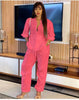 Pink solid color jumpsuit with long sleeves, V-neck, and adjustable waist ties