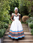White traditional South African dress with striped hem detail on model outdoors