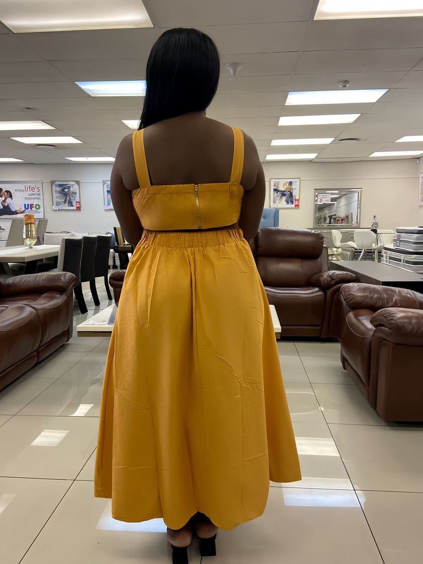 Back view of mustard yellow pleated sleeveless midi dress with high waist seam