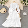 White pleated maxi dress with V-neck, long sleeves, and waist belt detail