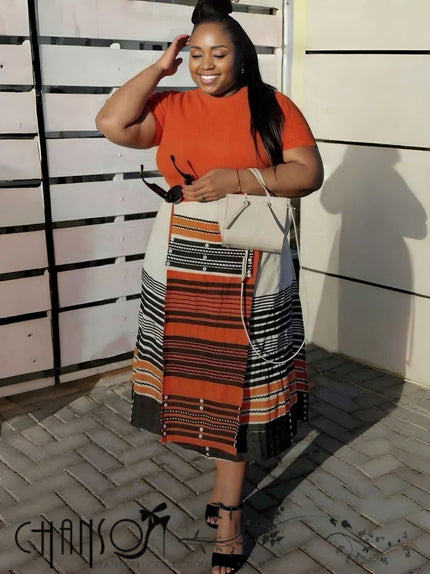 Geometric stripe print dress, orange-red crewneck bodice and patterned skirt with contrast trim