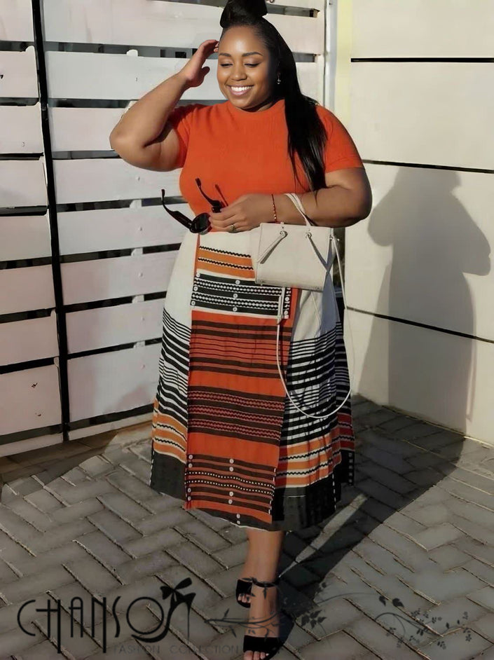 Geometric stripe print dress, orange-red crewneck bodice and patterned skirt with contrast trim