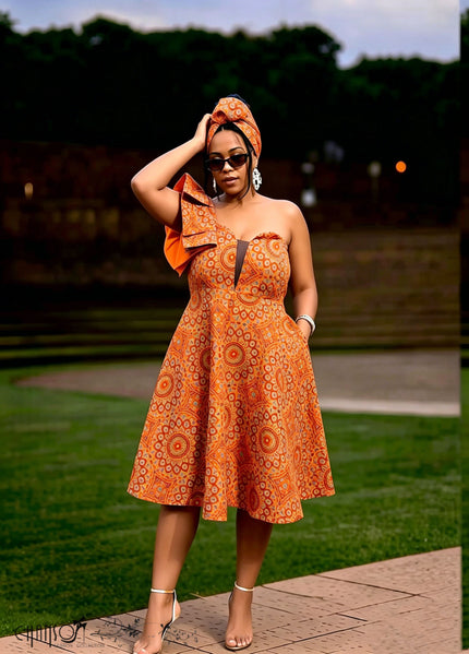 Orange-red one-shoulder ruffle dress with circular African print and knee-length flare