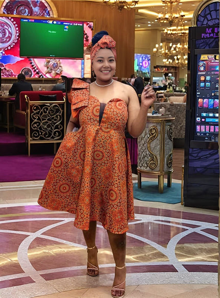 Orange-red one-shoulder ruffle midi dress with bold circular print