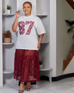 Twin set: white sequin number T‑shirt with maroon lace midi skirt, side view