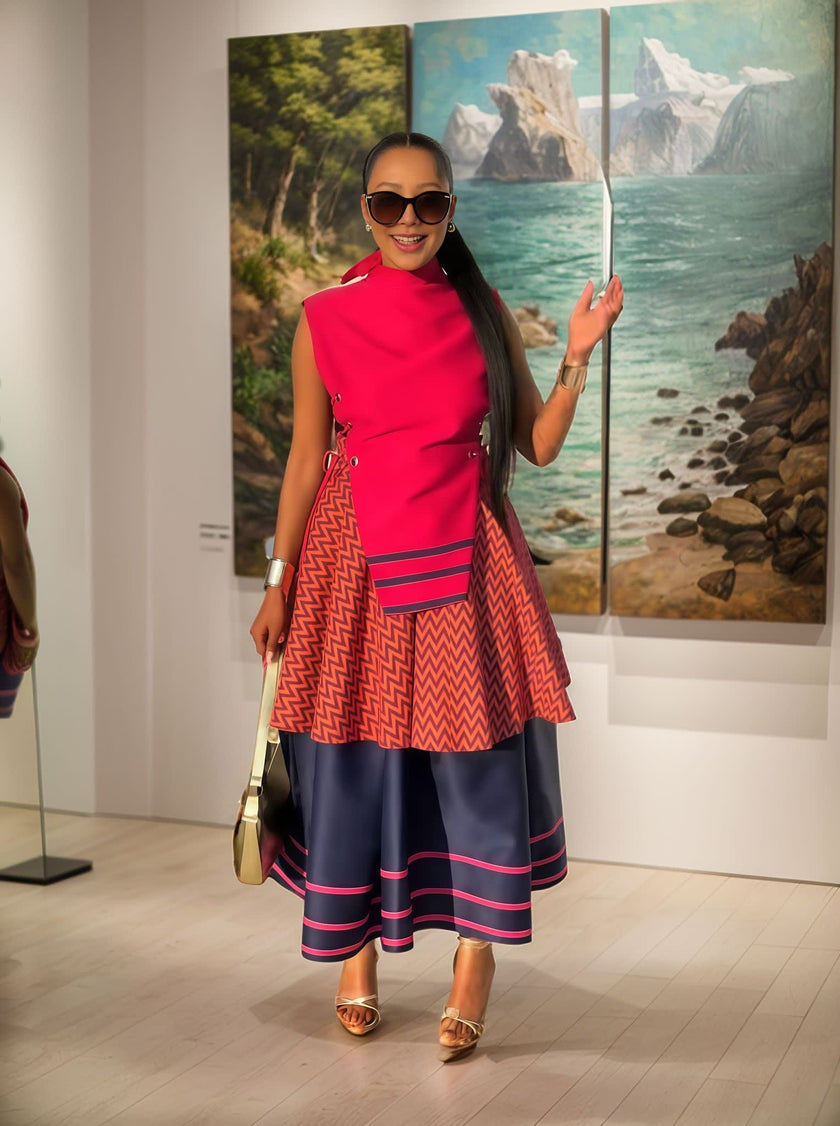 Layered midi dress with red high-neck bodice and zigzag geometric skirt, navy trim.